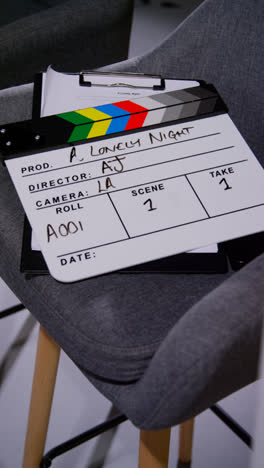 Vertical-Video-Close-Up-Of-Film-Clapperboard-Or-Slate-With-Production-Details-And-Script-Shooting-Movie-Or-Video-In-Studio-1